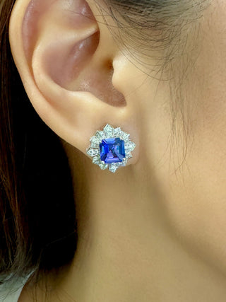 Close-up of an ear wearing a blue gemstone earring with a halo of diamonds.